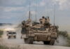 Armored Multi-Purpose Vehicle in field test, accompanied by Humvees