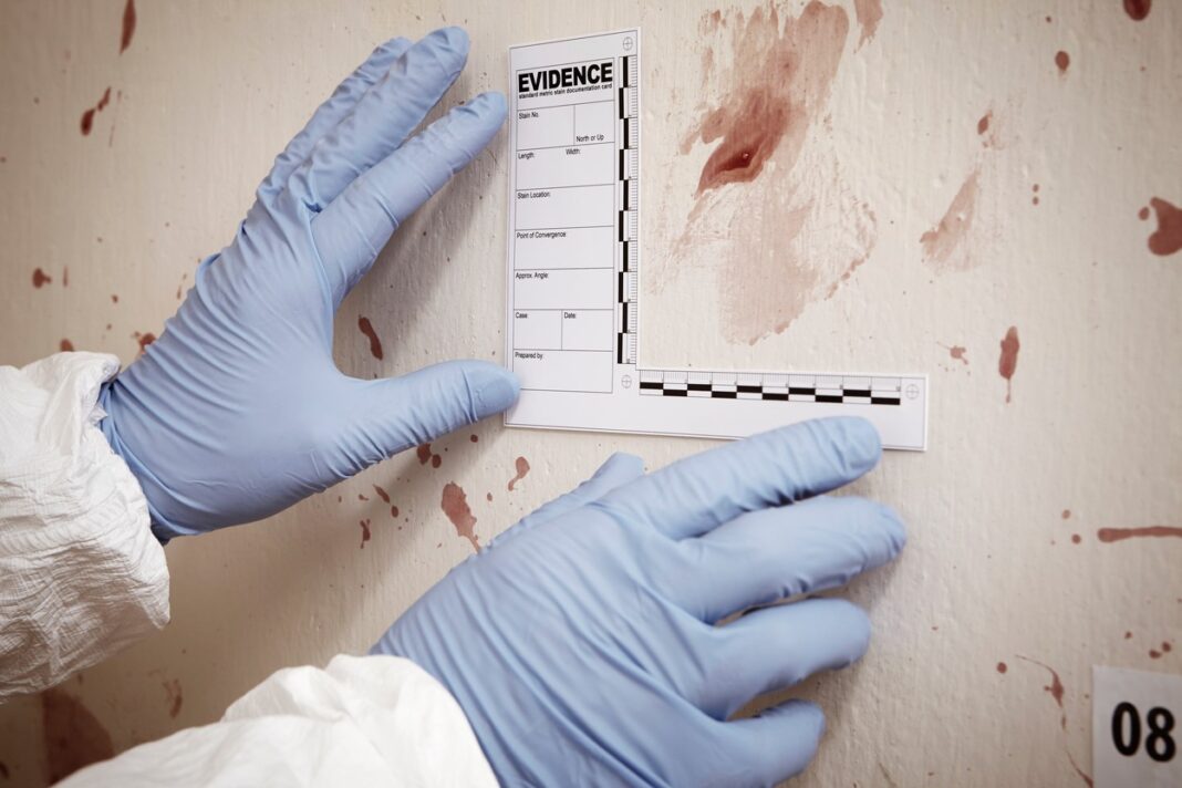 Technician on crime scene collecting evidences of blood stains