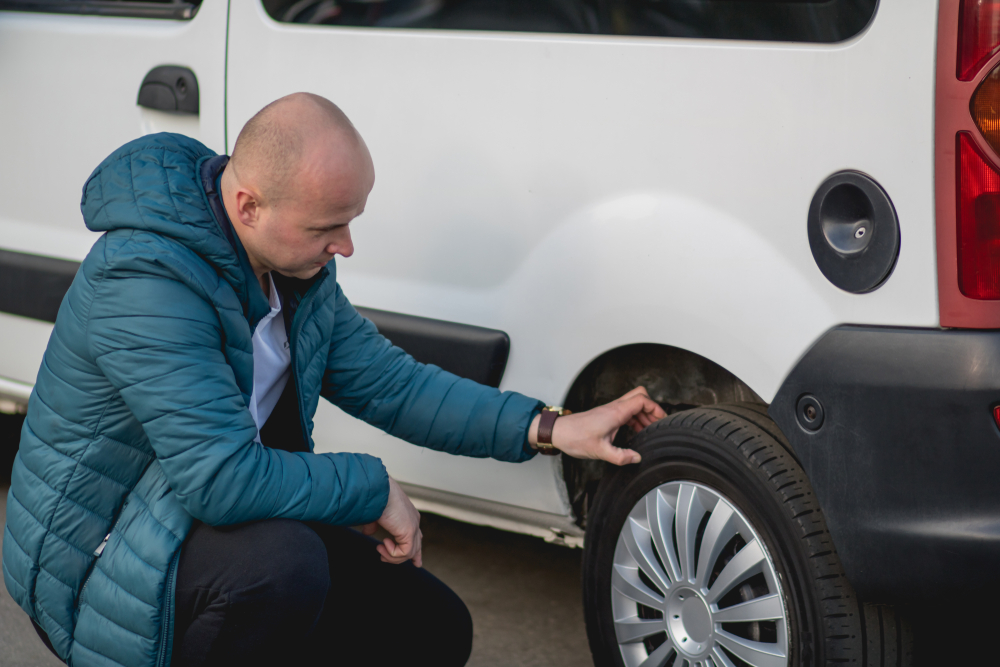The,Man,Crouched,Beside,The,Wheel,Of,The,Car,And