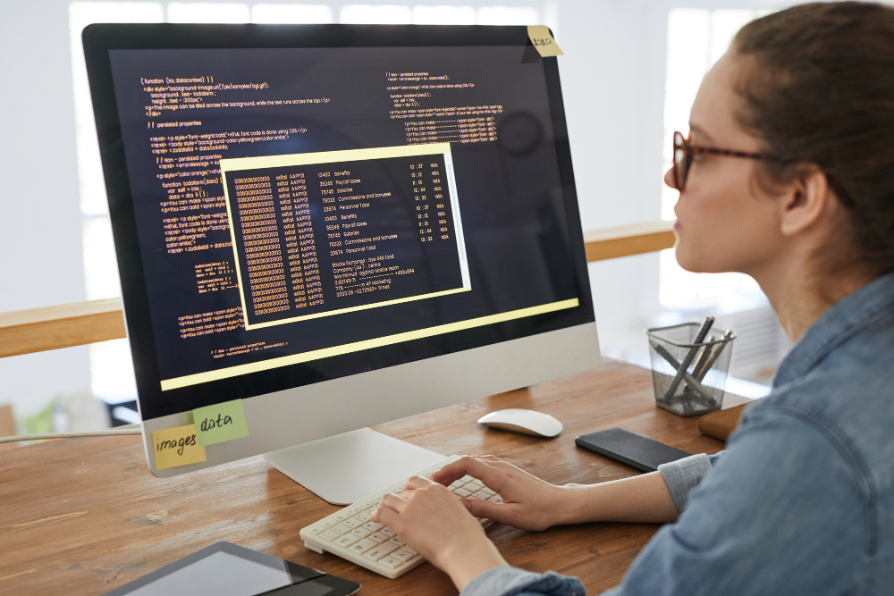 portrait-young-woman-writing-programming-code-computer-screen-while-working-desk-contemporary-office-interior-copy-space