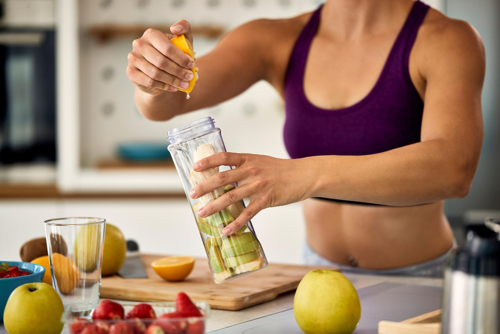 unrecognizable-sportswoman-using-lemon-while-making-fruit-smoothie-home